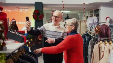 Xmas 'taki yaşlı çift alışveriş merkezinin giyim mağazasında torunuyla internet üzerinden konuşuyor ve Noel aile toplantısından önce hediye olarak şık spor ceketler seçmesini istiyor.