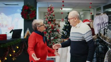 Mutlu yaşlı çift, Noel 'de Noel' de Noel 'de aile üyelerine hediye bulmak için kostüm mağazasında dans ediyor.