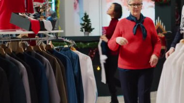 Bir kadın Noel alışverişinde kocasıyla kostüm mağazalarının raflarını karıştırıyor. Kış tatilinde oğluna hediye olarak şık kıyafetler arayan yaşlı bir çift.