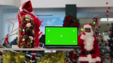 Xmas dekore edilmiş giyim mağazası masasındaki model dizüstü bilgisayar ürünler hakkında bilgi veriyor. Alışveriş merkezindeki moda mağazasında yeşil ekran cihazı kıyafet fiyatlarına bakmak için kullanışlı