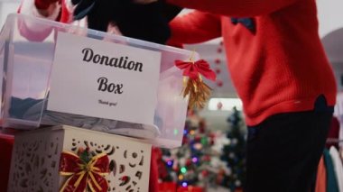 Moda mağazasındaki bağış konteynırının yakın çekimi. Noel tatilinde insani yardım için kıyafet bağışlayan neşeli ruhlardan etkilenen cömert müşteriler.
