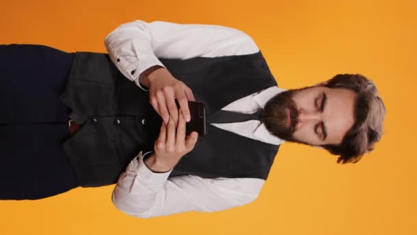 Vertikal Video Diner Anställd Messagging Smartphone Poserar Mot Gul Bakgrund — Stockvideo