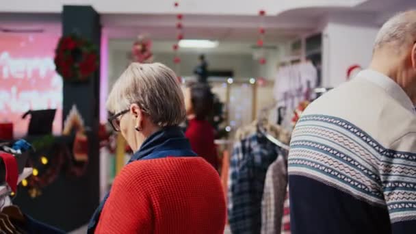 Seksenlik Müşteriler Kış Tatili Sezonunda Şenlikli Moda Mağazasında Elbise Raflarına — Stok video