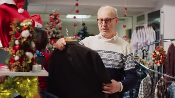 Oudere Man Onderzoekt Elegante Blazers Drukke Drukke Winkel Tijdens Wintervakantie — Stockvideo