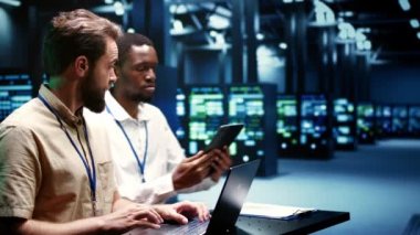 Yazılım sorunlarını belirlemek ve düzeltmek için veri merkezi elektronik tanı testleri yapan meslektaşlar. Kritik sistemleri onarmak, kusurları kontrol etmek için dizüstü bilgisayar ve tablet kullanan mekanikler