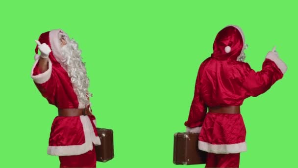 圣诞老人的公文包搭便车穿过绿屏的背景 他穿着节日服装 头戴帽子 留着胡子 想出去走走 有自信的男子 身穿与手提箱搭配的连衣裙 — 图库视频影像