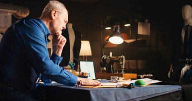 Erkek tasarımcı baskı altında, giysi ürünleri konusunda hayal kırıklığına uğramış hissediyor. Lüks kıyafetler yapmaya çalışan kıdemli terzi, mükemmel tasarım bulamayan stresli bir zanaatkar..