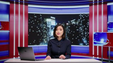 Asyalı haber spikeri televizyondaki yeni uluslararası materyaller hakkında canlı yayına ev sahipliği yapıyor. Dünya haberlerini sunan kadın gazeteci, son anonslar hakkında yorum yapıyor.