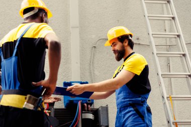 Isıtma, havalandırma ve havalandırma sistemlerini tamir ve bakımını yapan hassas servis elemanları. Yoğunlaştırıcı yıllık kontrol için görevlendirilmiş deneyimli profesyoneller, panoya rapor yazıyorlar