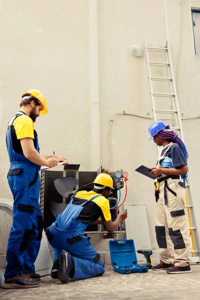 Różnorodna Załoga Certyfikowanych Techników Pracujących Zewnątrz Sprawdzających Utrudnione Filtry Powietrza — Zdjęcie stockowe