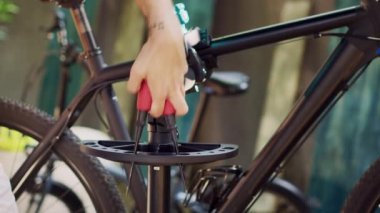 Beyaz adamın açık havada bisiklet bakımı için özel iş aletleri seçerken detaylı görüntüsü. Modern bisiklet tamiri için çeşitli ekipmanları tutan ve düzenleyen ellerin yakın görüntüsü.