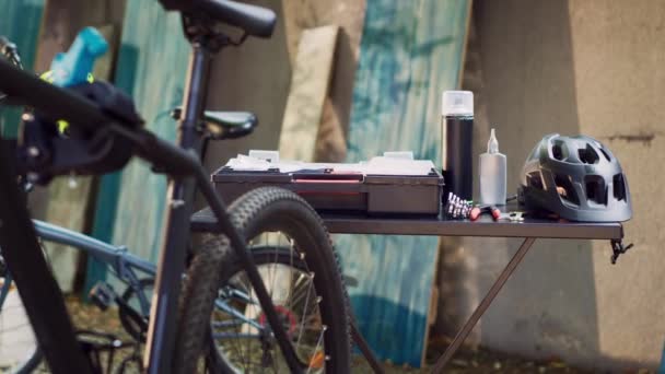 エキスパートツールキットのGlimpseは 他のツールと屋外の自転車のメンテナンスのためのヘルメットの品揃えと一緒にテーブルにきちんと配置されています 自転車修理のための専門装置 — ストック動画