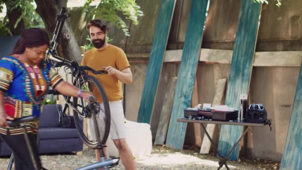 ホームヤードのスポーツ愛好家のカップルは トップノッチ機器を使用して自転車を修理しています エネルギッシュなアフリカ系アメリカ人女性と彼女のパートナーは 定期的なバイクのアップキーと調整に従事 — ストック動画