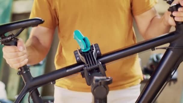 积极的高加索人把自行车身体放置和夹紧 以便修理支架 进行安全的室外维修 确保和调整自行车以准备在院子里维修的年轻人 — 图库视频影像