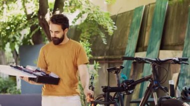 Sağlıklı atletik beyaz adam bisiklet bakımı için özel alet çantasını evin bahçesinde taşıyor. Spor düşkünü aktif erkek bisikletçi dışarıda bisiklet tamiri için profesyonel ekipman düzenliyor..