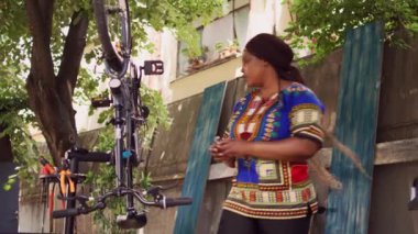 Özel iş aletleriyle bisiklet lastiği tamir ve ayarlama yapan aktif genç bir kadın. Sağlıklı spor düşkünü Afrikalı Amerikalı kadın profesyonel alet çantasıyla bisiklet tekerleğini sağlama aldı..