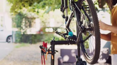 Spor düşkünü bir adam modern bisikleti profesyonel ekipmanlarla tamir etmeye kendini kaptırdı. Aktif beyaz erkek bisikletçi kendinden emin bisiklet zincirini tamir ediyor ve yaz tatili bisikleti lastiklerini inceliyor..