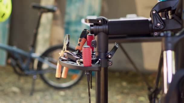 自転車のメンテナンスの準備ができている修理スタンドに配置された専門機器の品揃え 自転車修理や庭での修復のためのさまざまな作業ツールのズームインショット — ストック動画