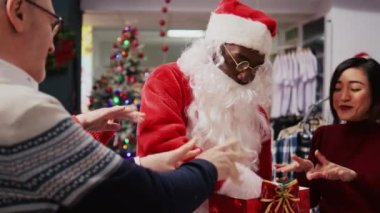 Noel Baba kostümü giyen, Noel Baba kostümlü, hediye kutusunu elinde tutan, piyango bileti kutusu gibi davranan, neşeli müşteriler arasında rastgele yaşlı bir adam çizen bir satıcı.