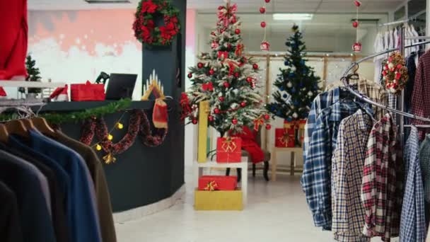 过冬的时候 多利在充满装饰精美的圣诞树 花环和装饰品的节日服装店里拍照 空荡荡的时装店 架子上有衣服 — 图库视频影像