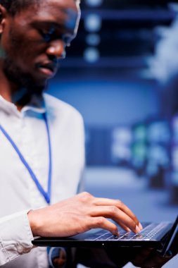 Bilgisayar bilimcilerinin internet içeriklerini çevrimiçi müşterilere ulaştıran sunucu satırlarının maintenaning sunuculuğunu yakından çek. Kritik sistemlerin işlevselliğini sağlamak için dizüstü bilgisayar kullanan Afrikalı Amerikalı denetçi