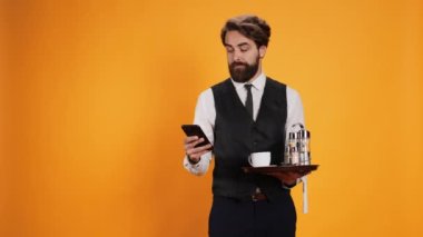 Lokanta tabağı ve çatal bıçak taşırken ve fotoğraf için poz verirken, yemek servisi çalışanı akıllı telefondan mesaj atıyor. Uzman garson mola sırasında telefonla uygulamaları kontrol ediyor.