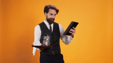 Kendini işine adamış personel, müşterilerine hizmet etmek için beş yıldızlı bir restoranda çalışırken tablet üzerindeki çeki hesaplar ve seçkin bir hizmet sunar. Uşak yemek tabağı ve modern bir alet taşıyor..