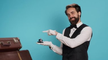 Otel hademesi servis zilini, kapıcı yardımını ve lüks bir servis sağlamak için zili işaret ediyor. Tramvay çantaları ve konukseverlik endüstrisine yardım eden genç profesyonel kapıcı..