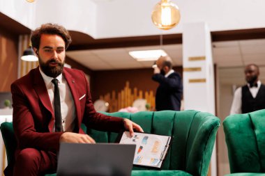 İş adamı, otelin dinlenme odasında iş arkadaşlarıyla uzaktan telekonferans görüşmelerine katılırken bilgisayarında video görüşmesi yapıyor. Çalışan iş için seyahat ediyor..