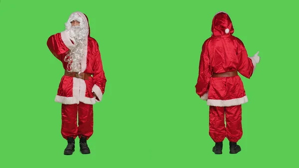 圣诞老人穿着圣人尼克服装 在工作室的绿屏背景下竖起大拇指 大拇指朝下 年轻人刻画冬天的主要人物 喜欢和不喜欢的手势 — 图库照片