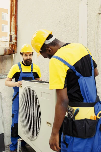 精确的服务人员和非洲裔美国同事为客户安装新的外部Hvac系统 精密线路机优化新型空调机性能 确保其高效运行 — 图库照片