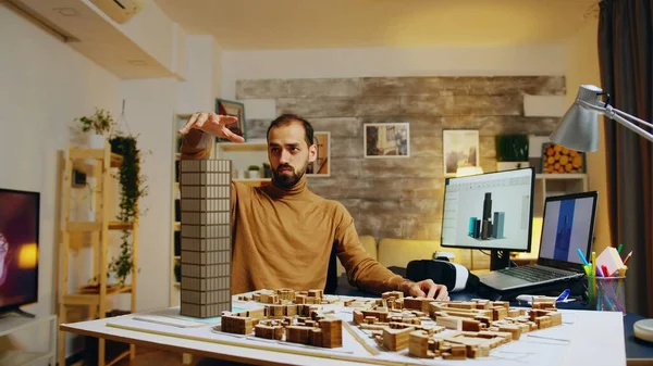 Architect working in office on creation of new residential complex, designing layout of skyscrapper buildings after finishing 3D graphic design architecture project on laptop