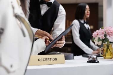 Çağdaş oteldeki Asyalı resepsiyonist müşteri kayıt formunu imzalamasına yardım ediyor. Lüks oteldeki otel odasını resepsiyondaki ziyaretçi kayıtlarına bakarak ayırtmak.