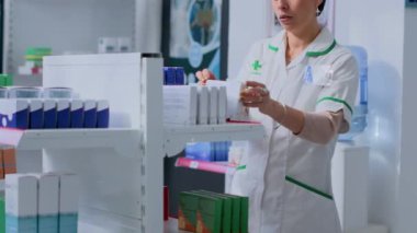 Sağlık uzmanı tıbbi önerilerle müşteriye yardımcı olmak için raflardaki ürünleri düzenlemekten mola alıyor. Eczacı farmakolojik ürün almak istiyor, eczacıdan tavsiye istiyor.