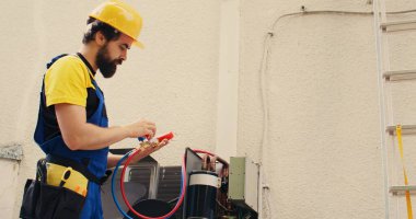 Elektrikçi, görev sırasında basınç ölçüm cihazını kalibre ediyor. HVAC sistem sıvıları ve gazlarının vakum basıncı okunuyor.