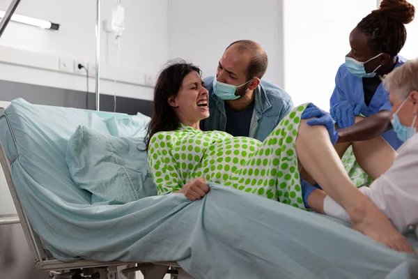 分娩时宫缩痛的妇女 医院病房剖腹产时分娩的医疗队 怀孕妇女在产科医院为孩子求医 — 图库照片