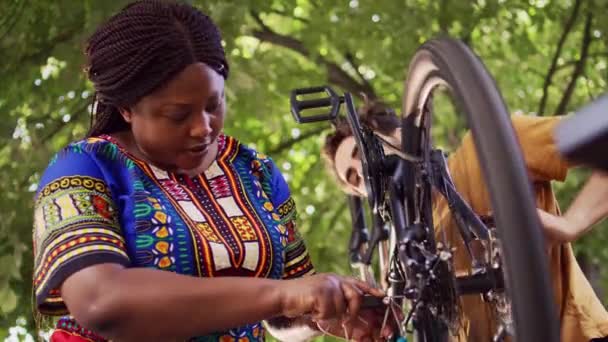 若くてスポーティなカップルが自転車のダメージを修復し 自宅の庭に特化したマルチトロール バイクの調整に適したアレンキーヘッドを選択する健康な白人男性と黒人女性 — ストック動画