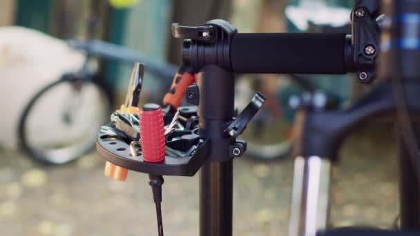 詳細なショットは 自転車のメンテナンス作業のために準備された修理スタンドに細心の注意を払って編成された専門機器の品揃えをキャプチャします 自転車修理のためのレンチドライバーやその他のツールの表示 — ストック動画