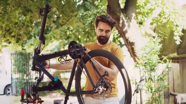 Νεαρός Αποφασισμένος Άνδρας Ελέγχει Εξαρτήματα Ποδηλάτων Στην Αυλή Για Ζημιές — Αρχείο Βίντεο
