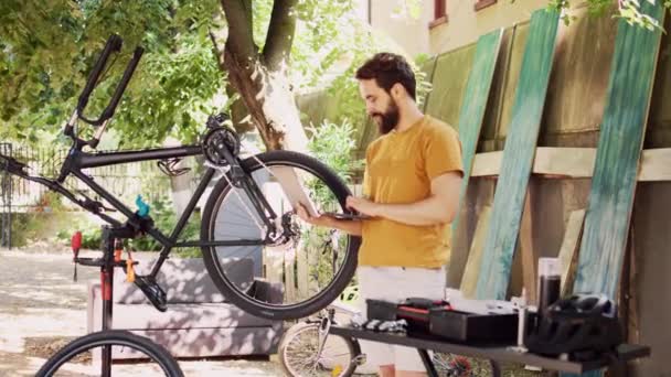 Νεαρός Καυκάσιος Συντηρεί Και Επισκευάζει Ποδήλατο Πληροφορίες Για Λάπτοπ Στην — Αρχείο Βίντεο
