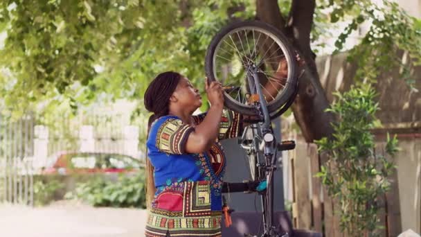 专门负责运动的非洲裔美国女性拆卸自行车轮胎 用于户外更换 瘦小的黑人妇女选择专门的多功能工具来修理自家院子里的自行车轮 — 图库视频影像