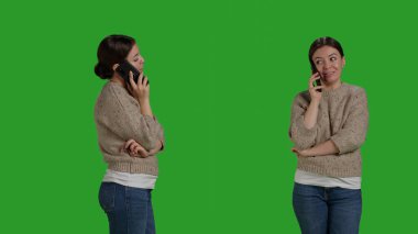 Close up of caucasian woman talking on smartphone line call, using mobile phone line to chat over full body greenscreen. Young cheerful person using telephone to talk to people in studio.