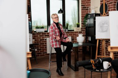 Yaratıcı sanatlar öğretmeni grup çizim dersleri sırasında öğrencilerle konuşuyor, insanlara çizim ve çizim yapmayı öğretiyor, yaratıcı atölye sırasında çeşitli çizim tekniklerini nasıl kullanacaklarını anlatıyor.