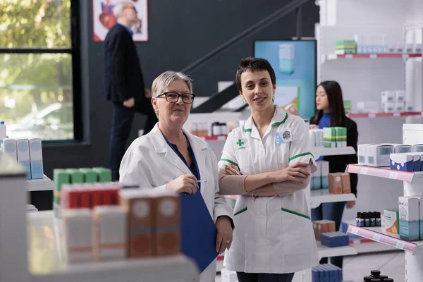 Zwei Lächelnde Pharmaangestellte Stehen Gang Der Apotheke Junge Und Ältere — Stockfoto