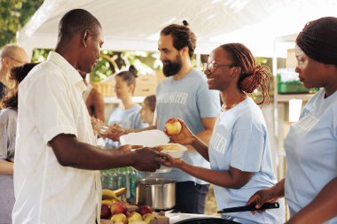 Afrikalı Amerikalı ve Kafkasyalı gönüllüler muhtaçlara bedava yiyecek ve ihtiyaçlar dağıtıyor. Evsizler barınağında hayır kurumu çalışanları daha az şanslı olanlara açlık yardımı ve insani yardım yapıyor..
