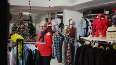 Müşteriler, kış tatilinde Noel süsleriyle süslenmiş meşgul giyim mağazalarının etrafında dolaşıyorlar. Moda mağazasında Xmas tanıtım satışları sırasında hediye alışverişi yapan müşteriler