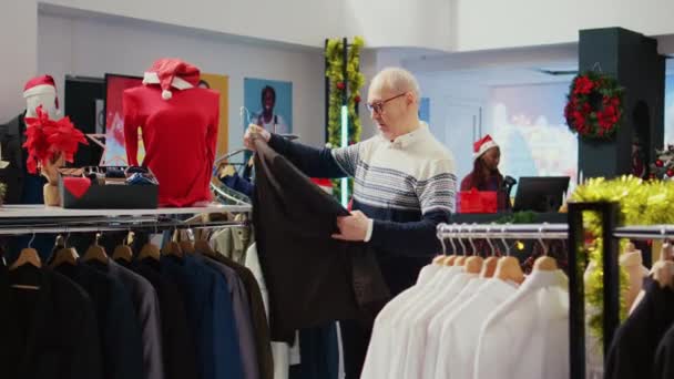 年长的顾客浏览衣架 想在圣诞假期为家人购买时髦的夹克作为礼物 老购物者寻找理想的礼物 — 图库视频影像