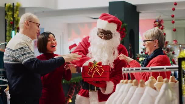 参加圣诞抽奖的顾客由穿着圣诞老人服装的员工在服装店里持仓 赢得冬季假期促销时装店比赛后 亚洲女性兴奋极了 — 图库视频影像