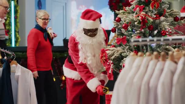 Весёлый Рабочий Одетый Санта Клаус Звонит Колокол Устанавливает Рождественские Подарки — стоковое видео