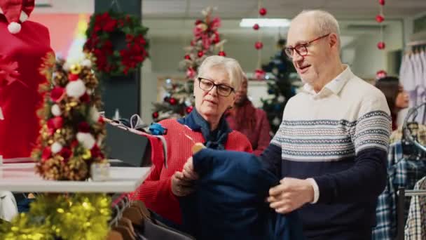Starszy Klient Przeglądający Świąteczne Ozdobne Szafki Sklepowe Odzieżą Żoną Świątecznym — Wideo stockowe